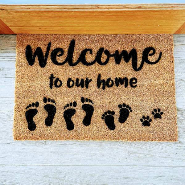 Doormat that says Welcome to our home with footprints and paw prints